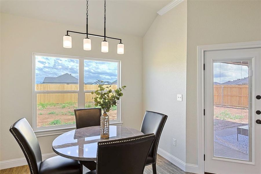 Dining area featuring a four-light linear chandelier, a large window, and a glass-paneled door