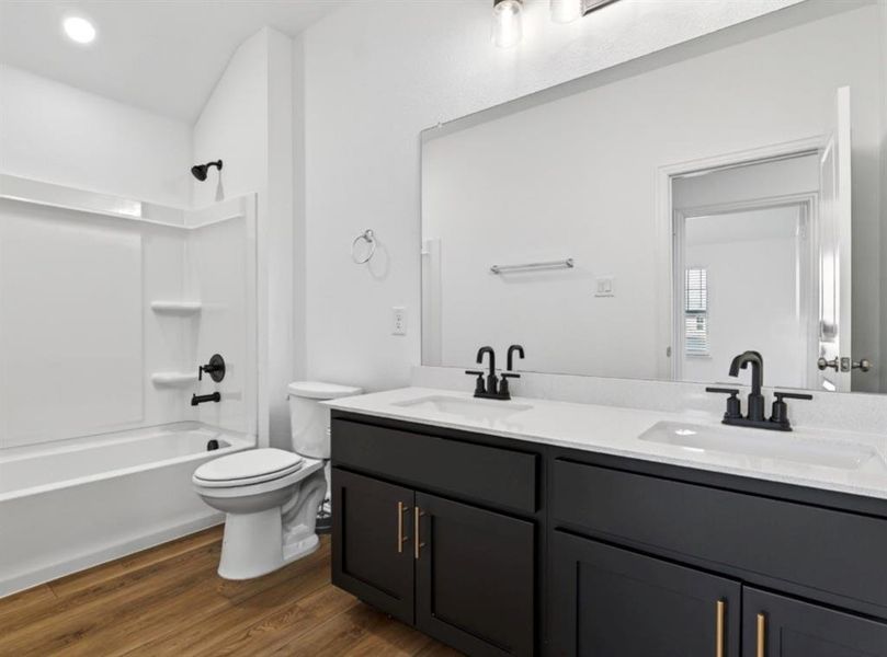 Full bath featuring double vanity, dark wood-style flooring, and bathtub / shower combination