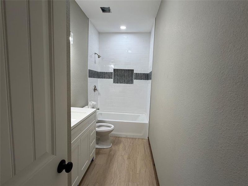 Bathroom featuring a white subway tile shower with a herringbone accent band and recessed niche