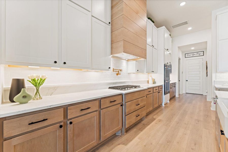 The chef-inspired kitchen combines timeless elegance with everyday functionality. Featuring an oversized quartz island with seating, custom cabinetry, designer lighting, pot filler above the gas cooktop, and sleek finishes throughout, this kitchen was designed to impress.