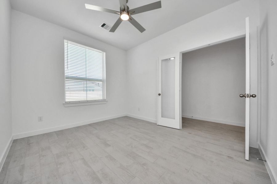 Experience the perfect blend of sophistication and warmth in this home office, boasting elegant wood-look tile flooring and flooded with natural light from expansive windows and French doors. Sample photo of completed home with similar floor plan. Actual colors and selections may vary.