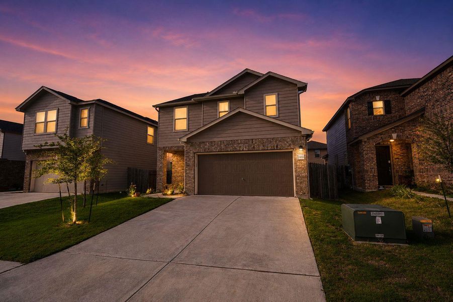 Dramatic sunset hues illuminate the brick and siding facade of this welcoming residence. Dramatic sunset hues illuminate the brick and siding facade of this welcoming residence.
