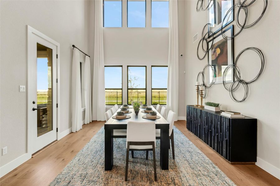Dining room featuring plenty of natural light, light wood-type flooring, and a high ceiling Dining room featuring plenty of natural light, light wood-type flooring, and a high ceiling