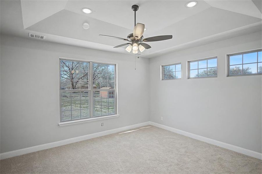 Carpeted empty room featuring ceiling fan, a raised ceiling, and recessed lighting