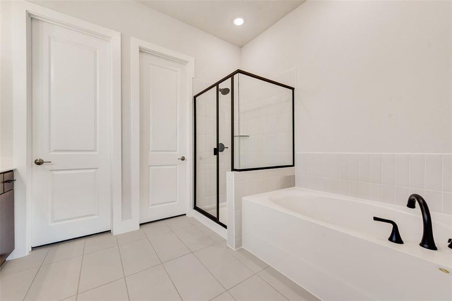 Bathroom with a bath, a shower stall, light tile patterned flooring, and vanity