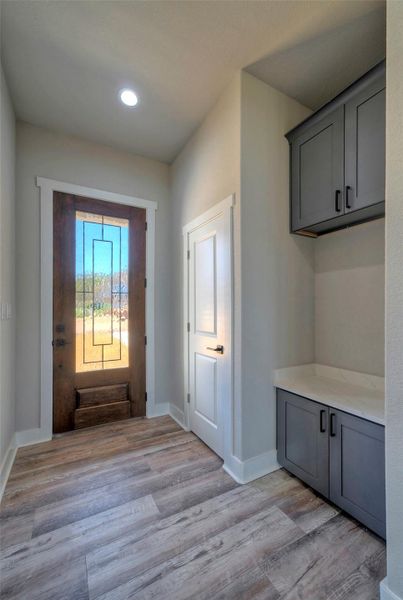 Warm wood tones from the custom front door complement the durable hard-surface flooring and cabinetry. Warm wood tones from the custom front door complement the durable hard-surface flooring and cabinetry.