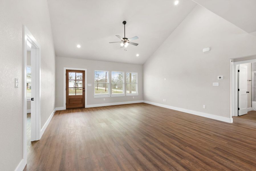 Unfurnished living room with dark wood-style floors, ceiling fan, vaulted ceiling, and recessed lighting