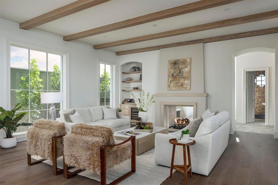 Living room with beam ceiling, healthy amount of natural light, a multi sided fireplace, and wood finished floors Living room with beam ceiling, healthy amount of natural light, a multi sided fireplace, and wood finished floors