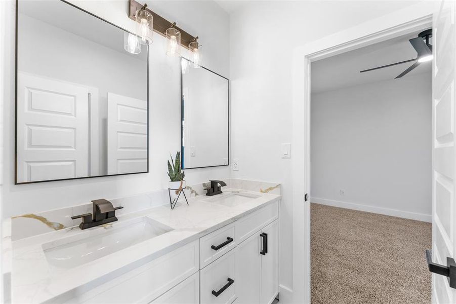 Full bathroom with double vanity, light carpet, and a ceiling fan