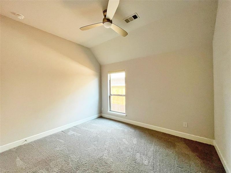 Unfurnished room with vaulted ceiling, carpet flooring, and a ceiling fan Unfurnished room with vaulted ceiling, carpet flooring, and a ceiling fan