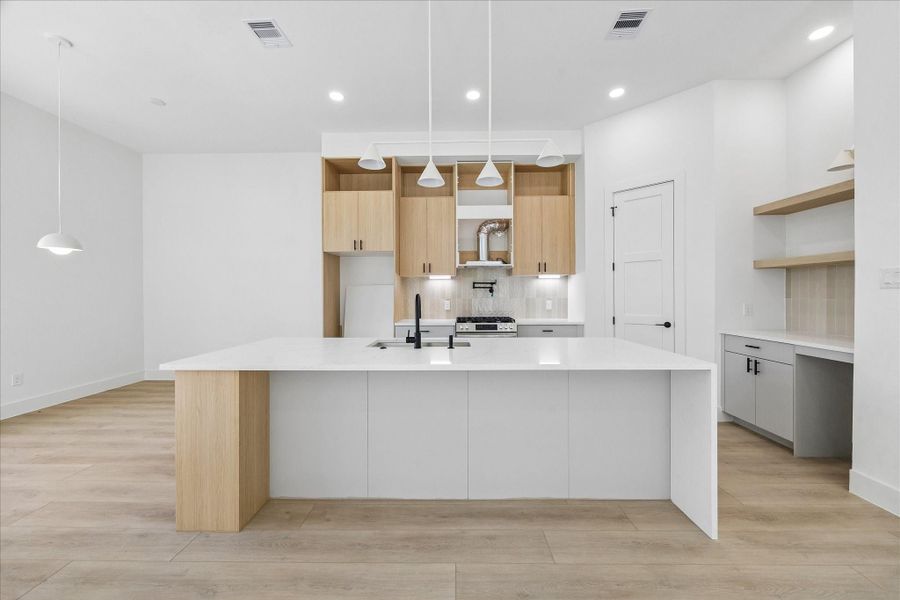 Vicenza Oak cabinetry, Soft Grey base cabinets, Aterra Blanca quartz countertops, matte black fixtures, and a full height designer backsplash create a kitchen that is both functional and beautifully curated.
