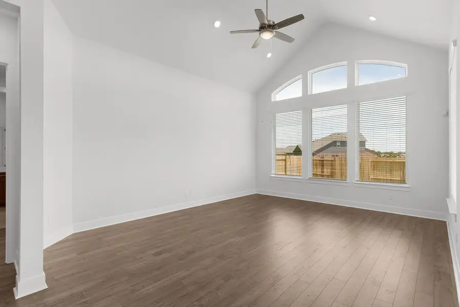 A well-lit living space features soaring vaulted ceilings, handsome hardwood floors, and expansive windows.