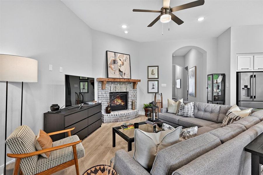 Living room featuring arched walkways, light wood finished floors, ceiling fan, a fireplace, and recessed lighting Living room featuring arched walkways, light wood finished floors, ceiling fan, a fireplace, and recessed lighting