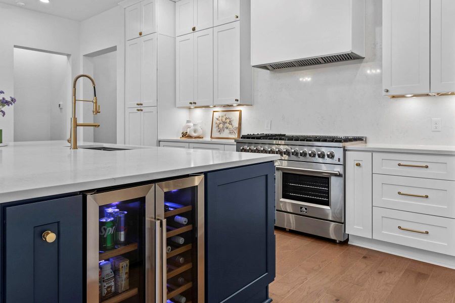 Kitchen with sink, custom exhaust hood, white cabinetry, light hardwood / wood-style flooring, and high end stove