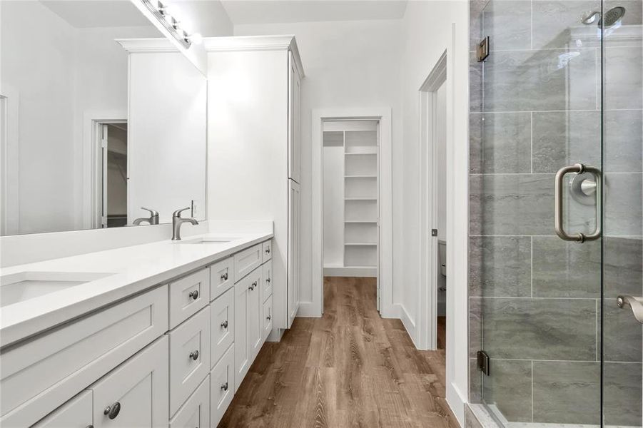 Bathroom with hardwood / wood-style floors, vanity, and walk in shower