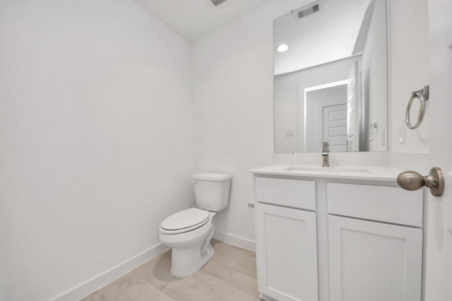 Sophisticated half bathroom adorned with contemporary finishes. The elegant 5-panel door welcomes you to a space where style meets functionality. Notice the sleek hardware accents that add a touch of modern charm. The vanity boasts light-colored countertops, beautifully complemented by a tasteful vanity light, creating a well-lit and inviting atmosphere. Sample photo of completed home with similar floor plan. Actual colors and selections may vary. Sophisticated half bathroom adorned with contemporary finishes. The elegant 5-panel door welcomes you to a space where style meets functionality. Notice the sleek hardware accents that add a touch of modern charm. The vanity boasts light-colored countertops, beautifully complemented by a tasteful vanity light, creating a well-lit and inviting atmosphere. Sample photo of completed home with similar floor plan. Actual colors and selections may vary.