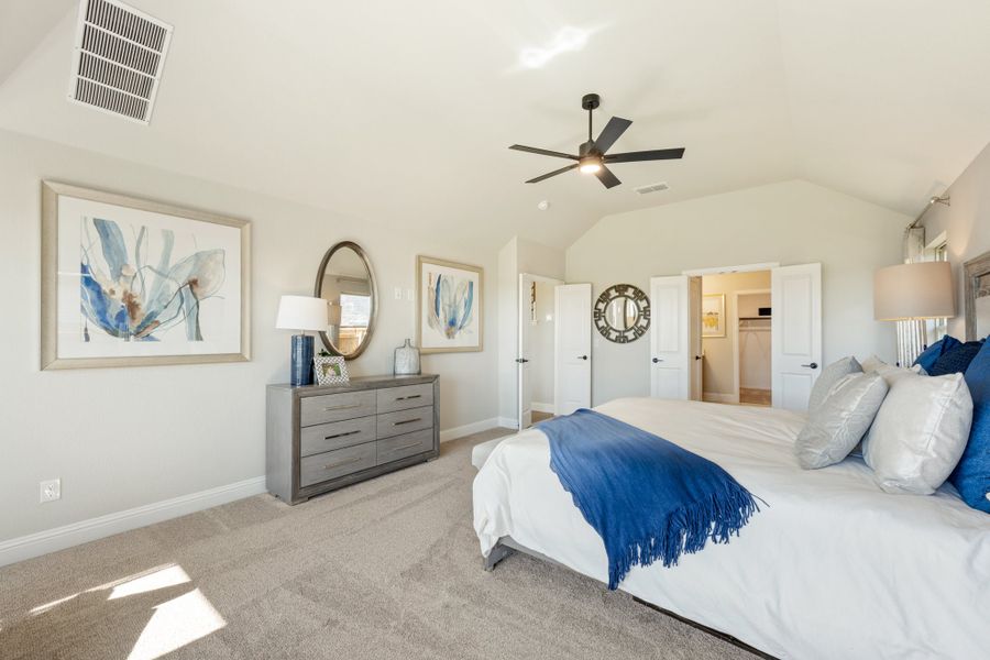 Master bedroom with vaulted ceiling, ceiling fan, carpet floors, and open walk-in closet doorway