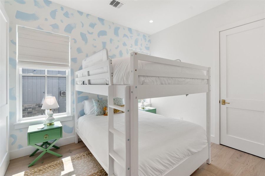 Bright and airy, this sleeping space features a playful accent wall and natural wood flooring. Bright and airy, this sleeping space features a playful accent wall and natural wood flooring.