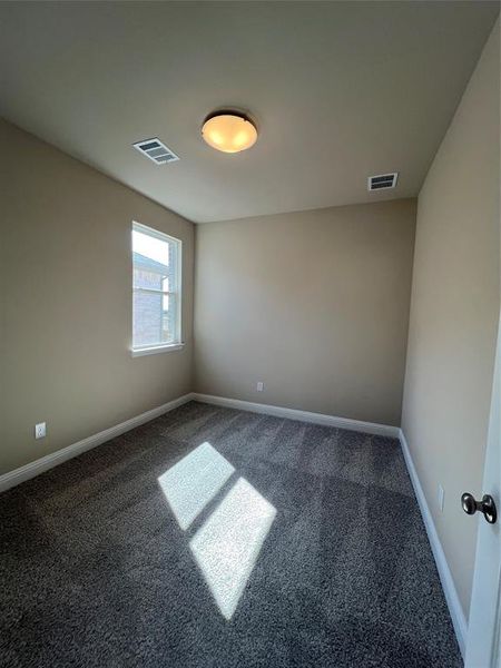 Carpeted spare room with visible vents and baseboards