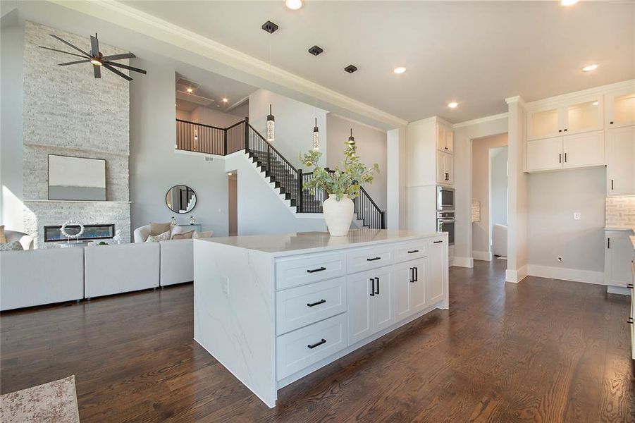 Kitchen with open floor plan, a fireplace, hanging light fixtures, white cabinetry, and recessed lighting Kitchen with open floor plan, a fireplace, hanging light fixtures, white cabinetry, and recessed lighting