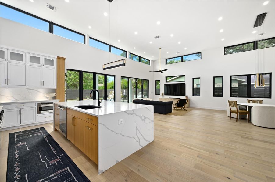 Kitchen featuring open floor plan, light wood-style floors, visible vents, and a sink