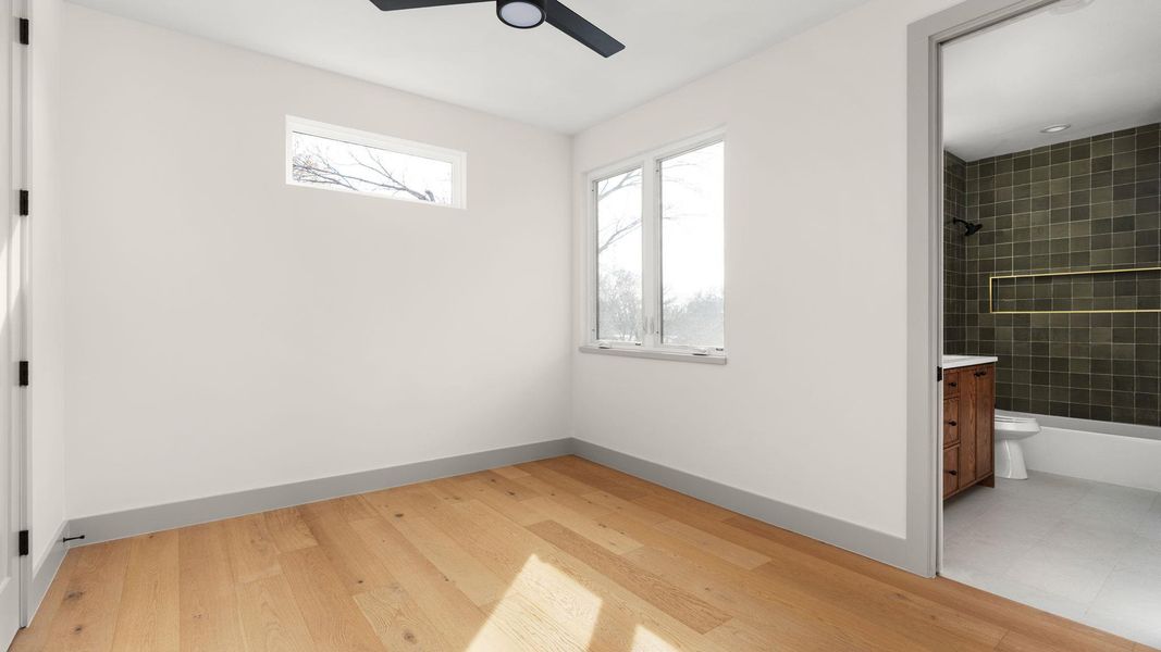 Unfurnished bedroom with light wood-style flooring, connected bathroom, and ceiling fan