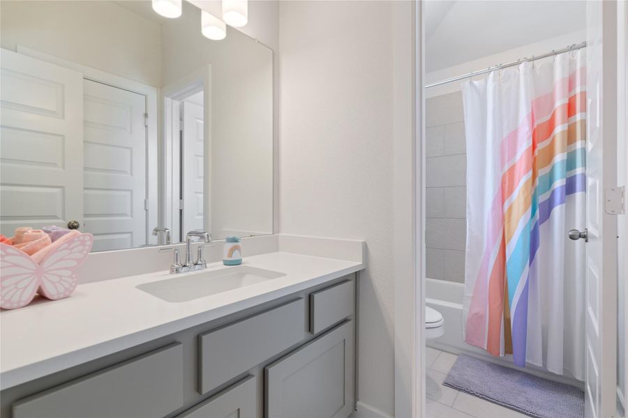 This full bathroom includes tile flooring and a bathtub/shower combo.