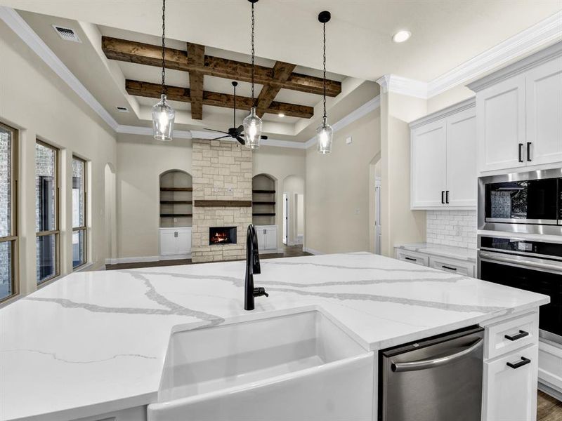 Kitchen featuring coffered ceiling, stainless steel appliances, sink, beamed ceiling, and white cabinetry