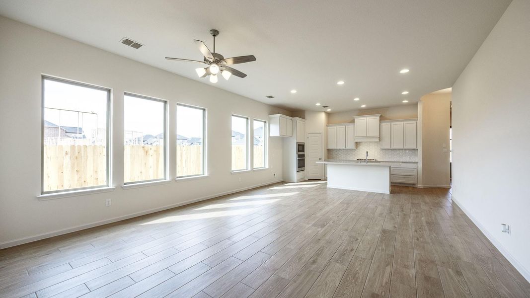 Unfurnished living room with ceiling fan, sink, and light wood-type flooring