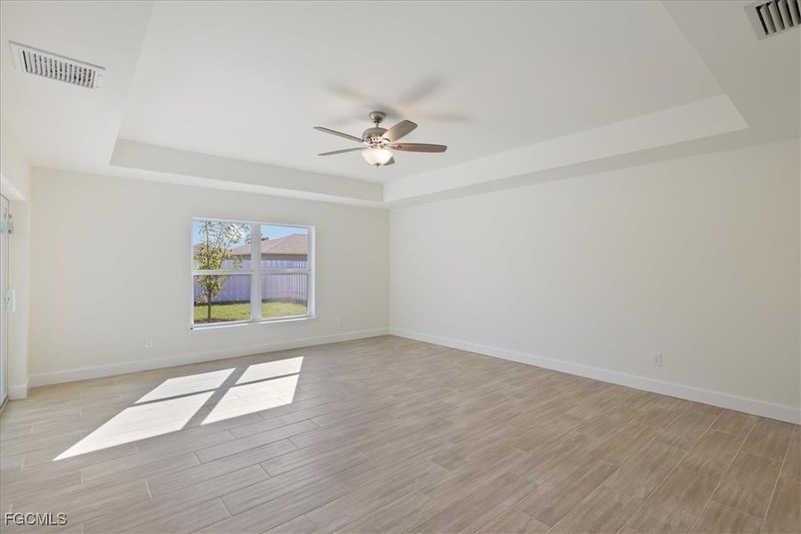 Spare room featuring a tray ceiling, wood finish floors, and ceiling fan