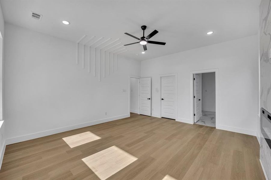 Unfurnished bedroom with ceiling fan, ensuite bath, and light hardwood / wood-style flooring