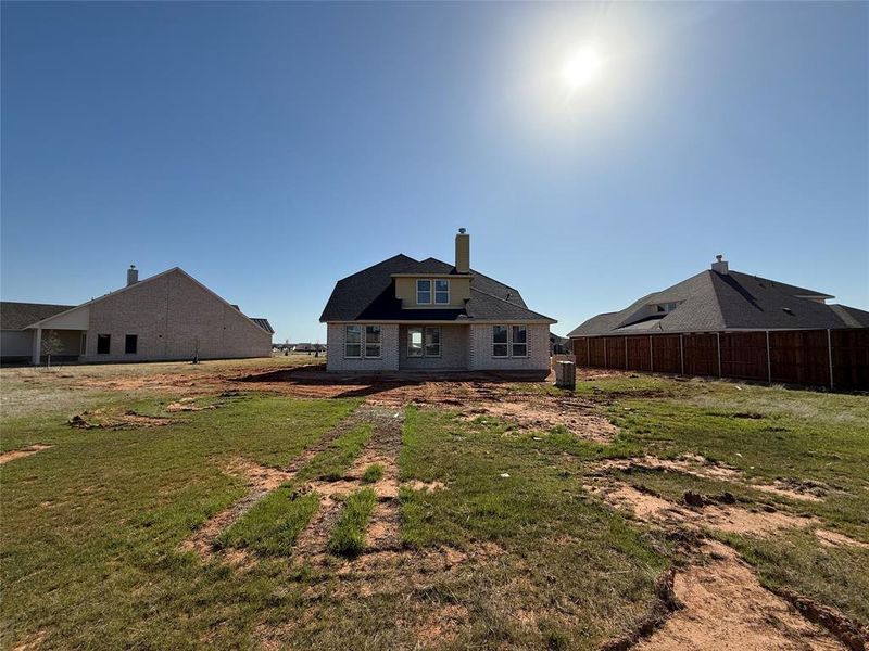 Rear view of house featuring a lawn, a chimney, and fence