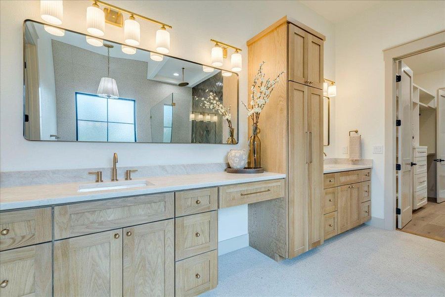 Dual vanities with stone counters and modern fixtures anchor this airy primary bathroom.