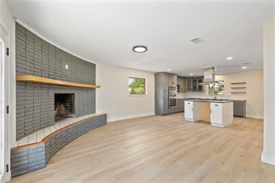Unfurnished living room with light wood-type flooring, a fireplace, and recessed lighting Unfurnished living room with light wood-type flooring, a fireplace, and recessed lighting