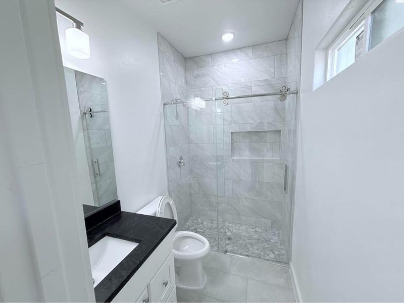 Full bath with vanity, a shower stall, and light tile patterned flooring Full bath with vanity, a shower stall, and light tile patterned flooring