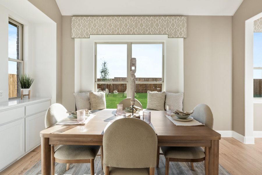 Dining area with wood table, upholstered chairs, built-in bench seating, and large window overlooking backyard