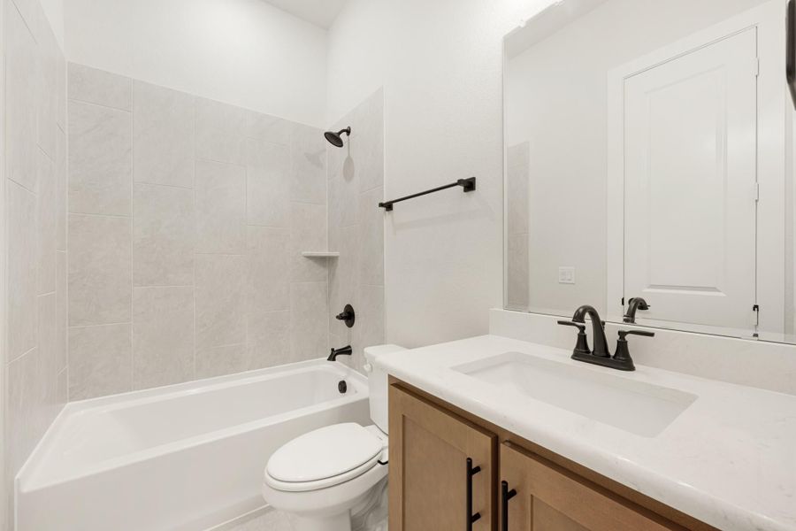 Bathroom with tiled tub-shower combo, wood vanity with white countertop, and matte black fixtures