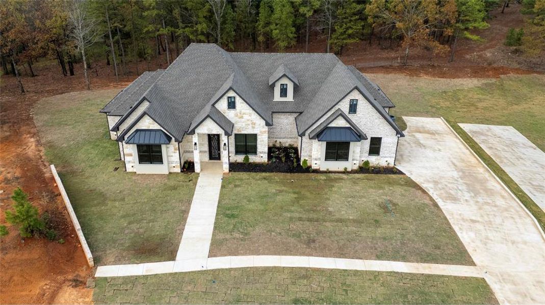 French country style house with stone siding, a front lawn, and a standing seam roof
