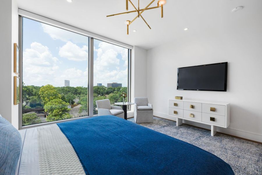 Another perspective of the primary bedroom with sitting area, highlights the views through floor to ceiling windows. Photos are of a similar unit with the same floor plan