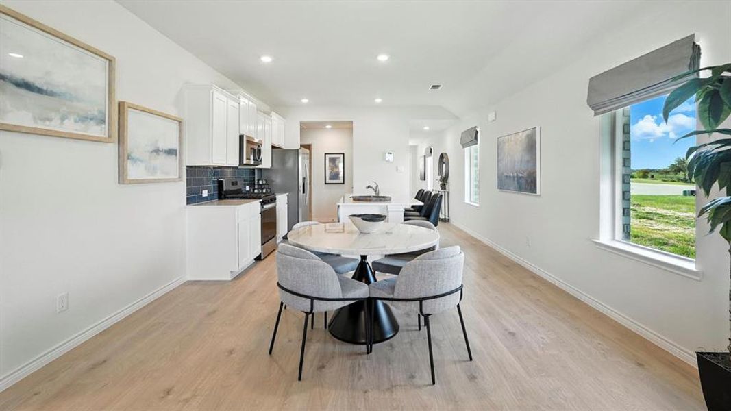 Dining room with light wood finished floors and recessed lighting