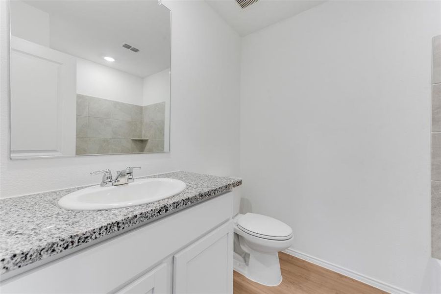 Bathroom featuring wood-type flooring, a shower, vanity, and toilet