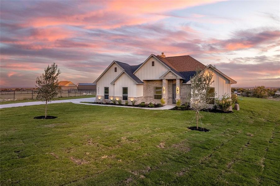 Modern farmhouse with stone siding, a chimney, and board and batten siding
