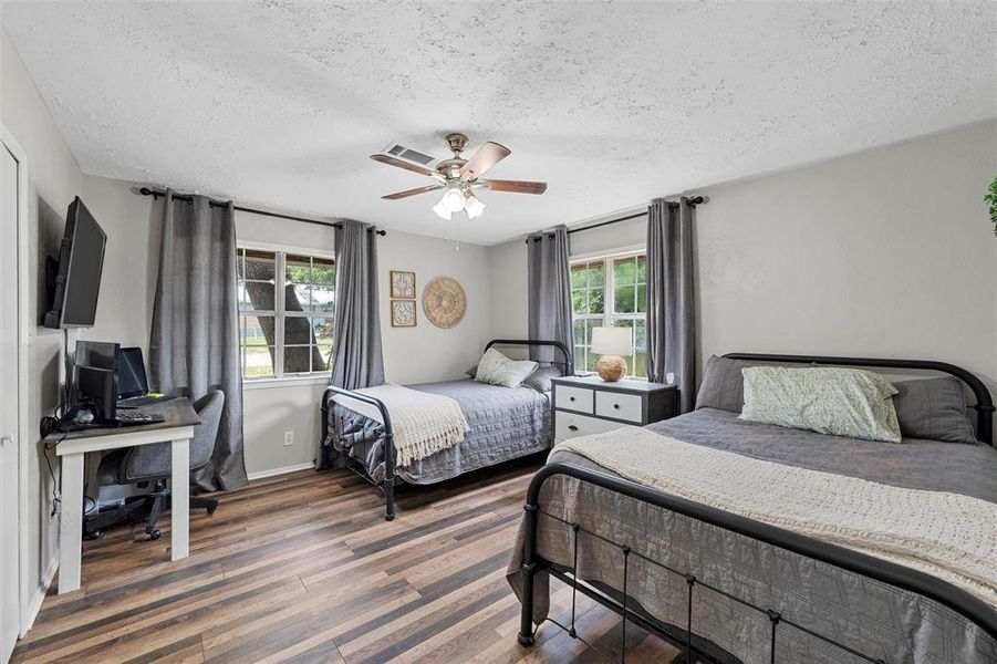 Bedroom with a textured ceiling, wood finished floors, a desk, a ceiling fan, and baseboards Bedroom with a textured ceiling, wood finished floors, a desk, a ceiling fan, and baseboards