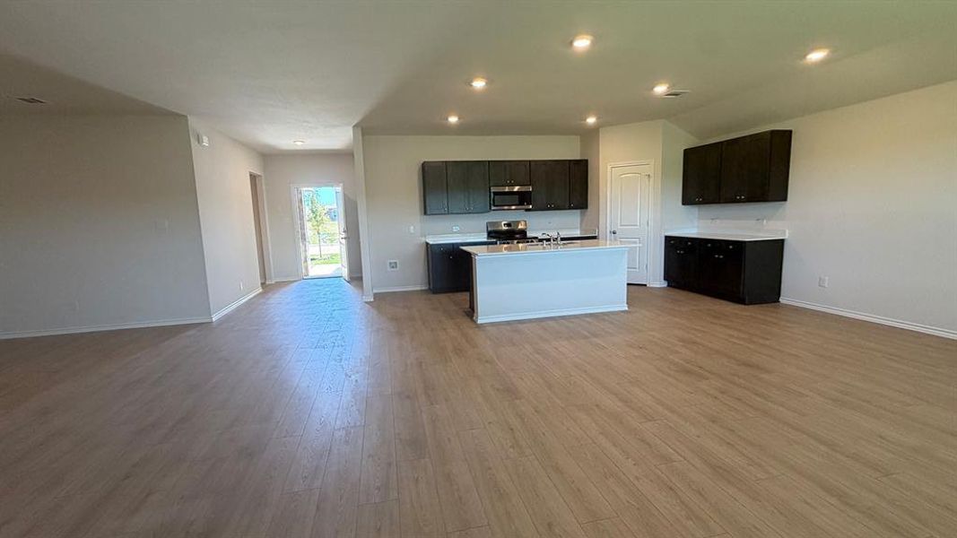 Open-concept living area with wood-finish flooring, recessed lighting, and light-toned walls