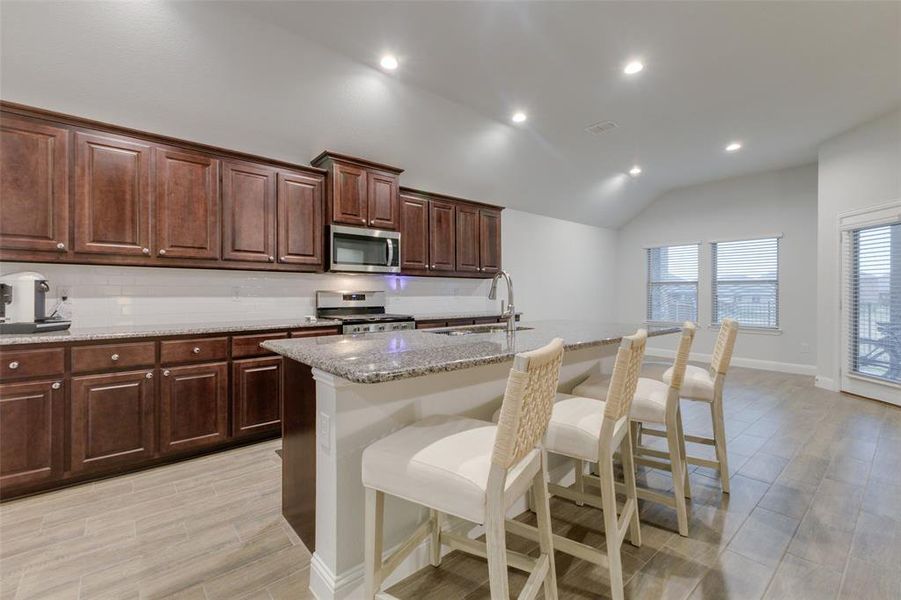 Kitchen featuring a kitchen breakfast bar, sink, an island with sink, and stainless steel appliances