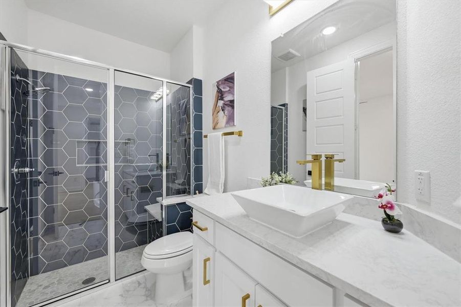 Spacious bathroom featuring a glass-enclosed shower with hexagonal tile, a built-in shower bench, and gold-finish hardware