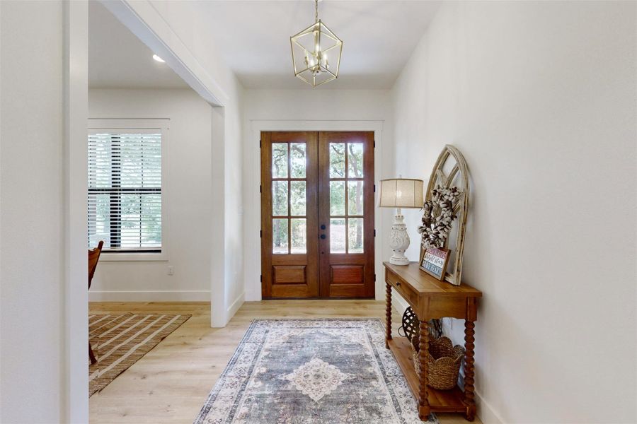 Entrance foyer with healthy amount of natural light, french doors, a chandelier, and wood finished floors