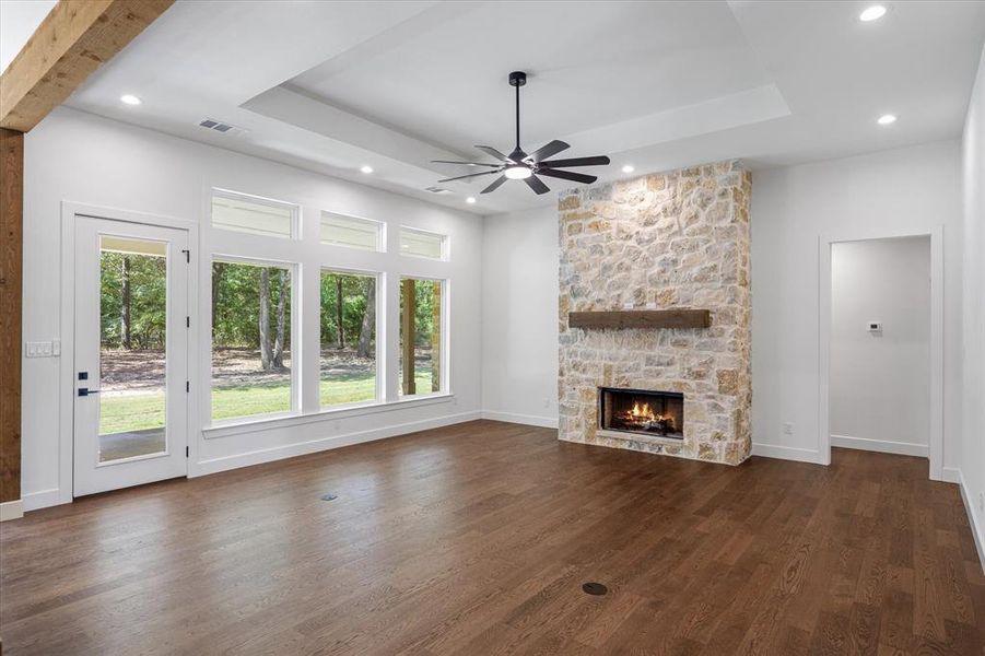 living room with a masonry fireplace, a tray ceiling, dark wood-style floors, a ceiling fan, and recessed lighting living room with a masonry fireplace, a tray ceiling, dark wood-style floors, a ceiling fan, and recessed lighting