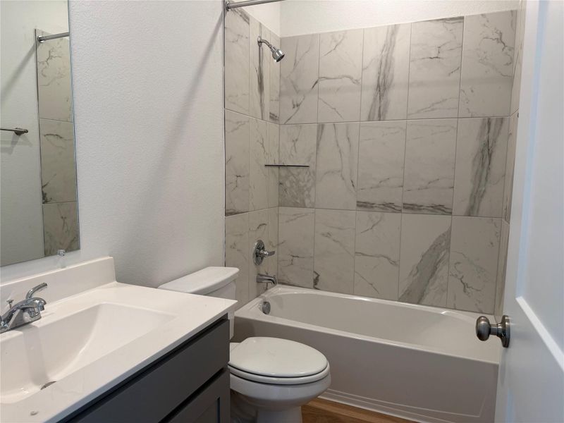 Full bath with shower / washtub combination, vanity, a textured wall, and wood finished floors Full bath with shower / washtub combination, vanity, a textured wall, and wood finished floors