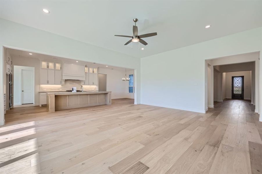 Unfurnished living room featuring light hardwood / wood-style floors, sink, and ceiling fan with notable chandelier